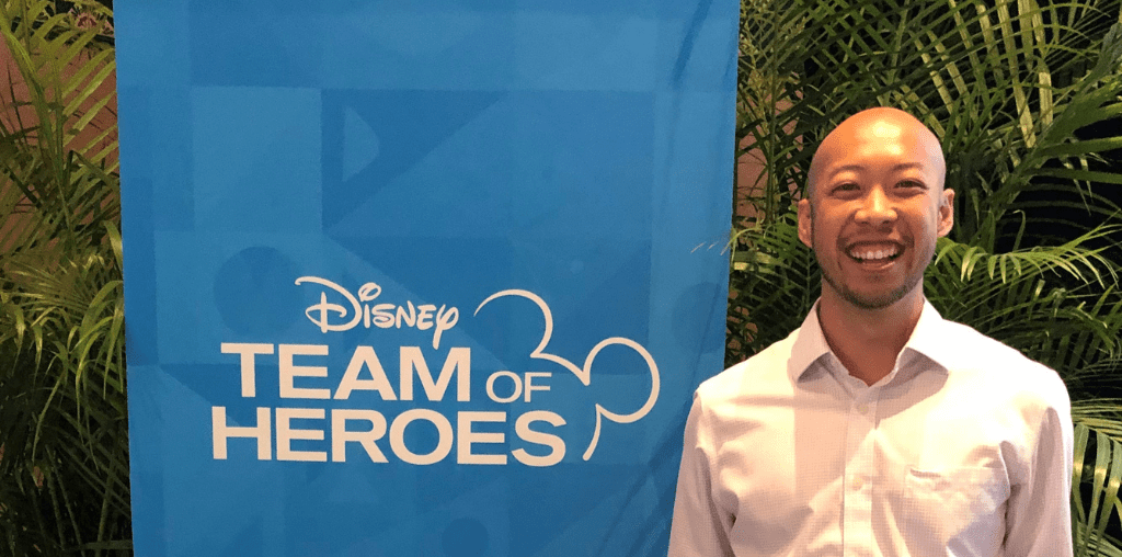 Daniel Pham stands next to a Disney Team of Heroes banner