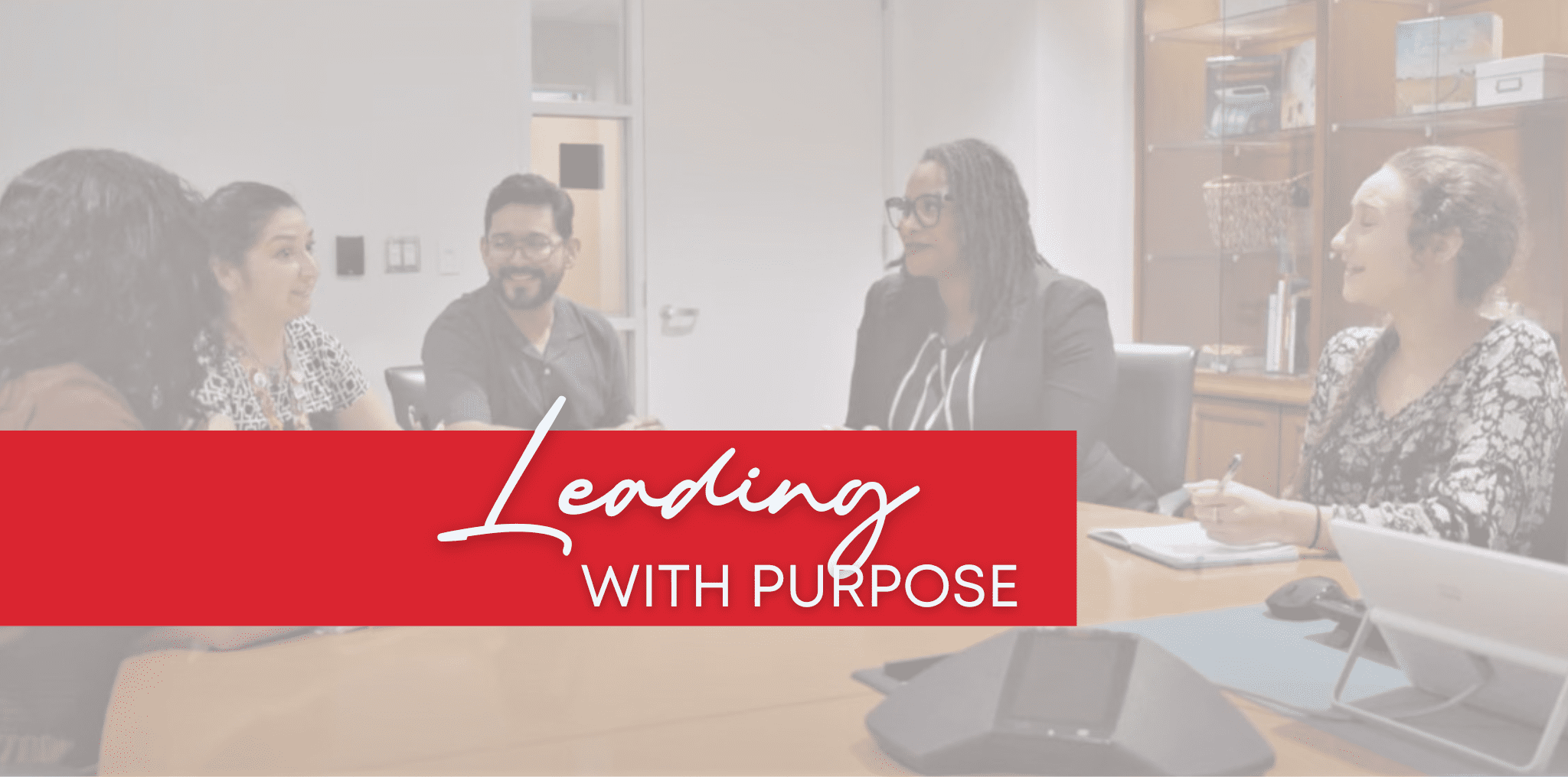 A healthcare leader sits at a conference table with her team members. Text reads "Leading with purpose."